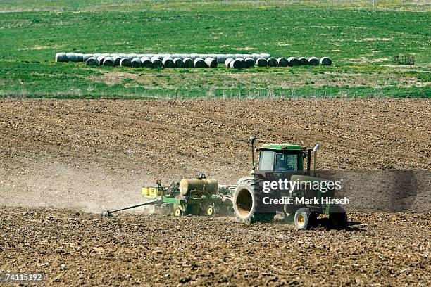 Iowa farmer Ernie "George" Goebel pulls a corn planter behind his John Deere tractor while planting corn in a field on the farm he was raised on May...