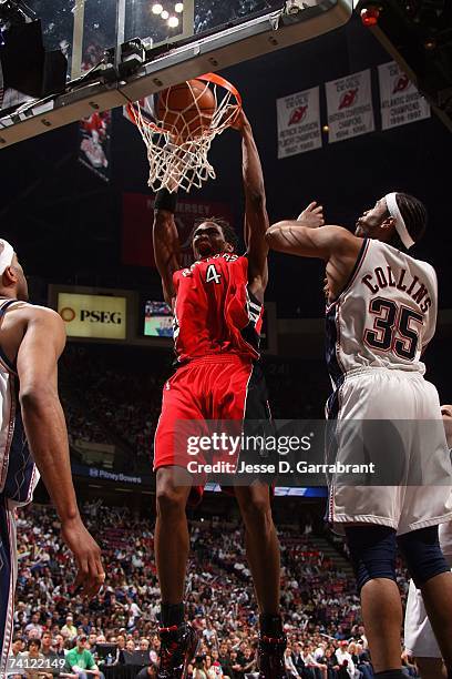 Chris Bosh of the Toronto Raptors dunks against Jason Collins of the New Jersey Nets in Game Six of the Eastern Conference Quarterfinals during the...