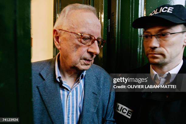 French satirical weekly Canard Enchaine's chief editor Claude Angeli leaves his office passing next to a policeman, 11 May 2007 in Paris, during a...