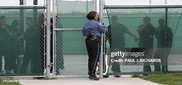 Raymondville, UNITED STATES: A guard secures the gate as female detainees stand in the exercise yard inside Homeland Security's Willacy Detention...