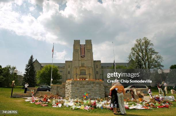 People walk along the edge of a large makeshift memorial, for all who died in last month's shooting rampage on campus, on the Drillfield in front of...