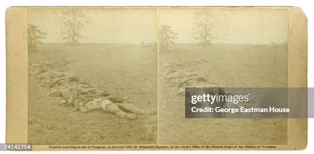 Stereoscopic view of a row of dead soldiers in a field, originally captioned as 'Gathered together for burial after the battle of Antietam,' mid to...