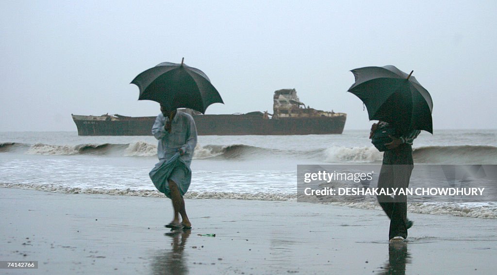 Bangladeshi tourists carry umbrellas as...