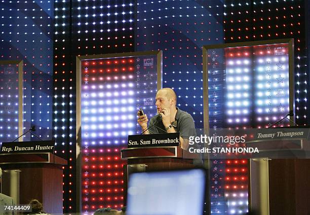 Columbia, UNITED STATES: A technician checks lighting at the podium for US Senator Sam Brownback , flanked by the podiums for US Rep. Duncan Hunter...