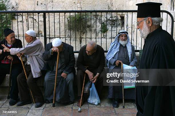 Christian priest passes elderly Palestinian men at the Damascus Gate May 14, 2007 in Jerusalem's Old City, Israel. Israel is marking the 40th...