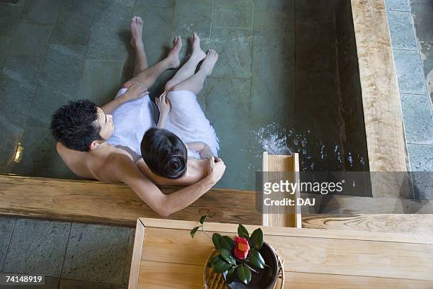 mid adult couple soaking in the hot spring bath together, high angle view - japanese women bath stock-fotos und bilder