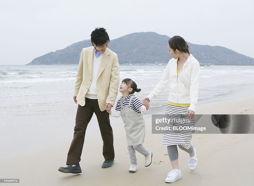 Japanese couple and girl walking with holding hands on beach