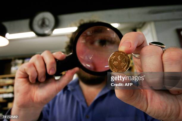 Numismatist David Pretty takes a closer look at the newly released Australian one dollar APEC coin at a Sydney coin dealer, 15 May 2007. Australia...