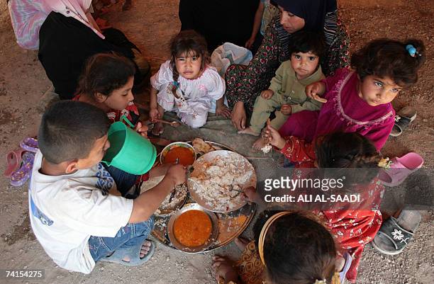 Iraqi refugees from the violence-ridden Diyala province, northeast of Baghdad, eat inside their tent, provided by the Iraqi Red Crescent Society in...