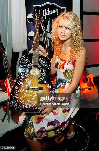 Country Artist Taylor Swift poses with the Gibson display in the Distinctive Assets gift lounge during the Academy of Country Music Awards held at...