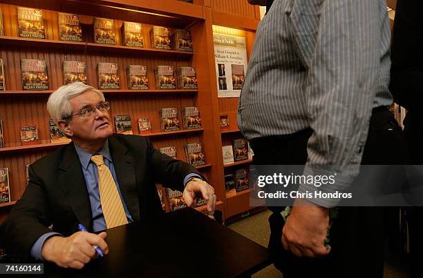 Former Speaker of the House Newt Gingrich looks up at a man as he signs copies of his book "Pearl Harbor: A Novel of December 8th" at a Barnes and...