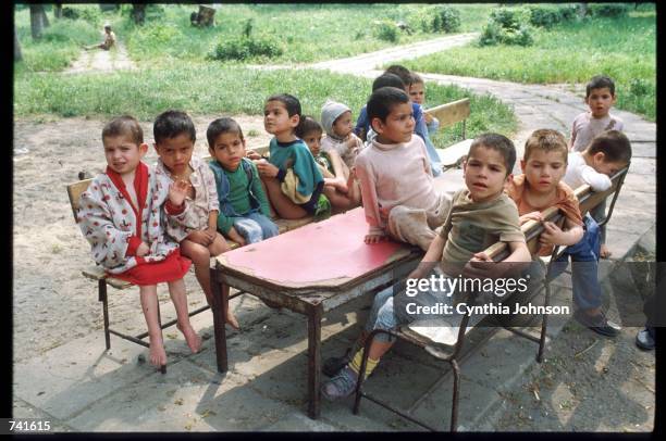 Children sit outside of an orphanage May 15, 1990 in Gradinari, Romania. Nicolae Ceausescu required women to bear at least five children causing the...