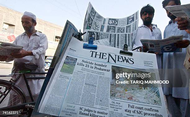 Pakistani men read newspaper carrying the news of a suicide attack at a road side stall in Peshawar, 16 May 2007, a day after a suicide attack. A...