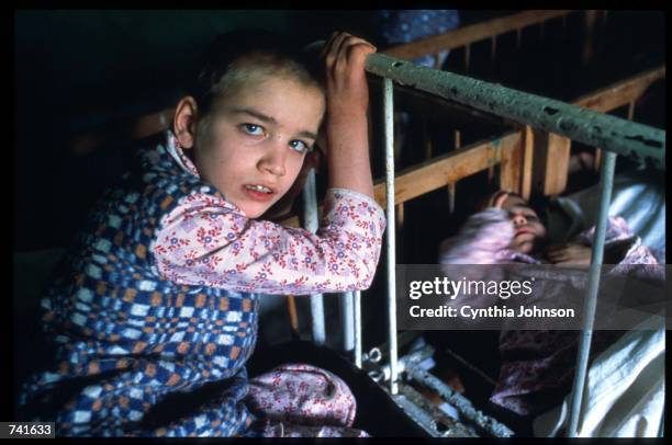 Young girl grips the bars of another childs bed May 15, 1990 in Romania. Under Nicolae Ceausescu policies women were required to bear at least five...