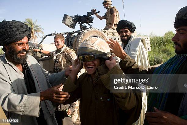 An Afghan teenager play with the helmet of a British Soldier from the Grenadier Guards during a reassurance patrol in a village, in a location in the...