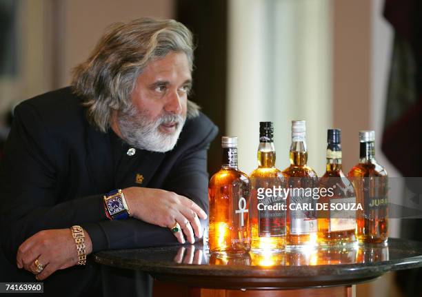 Glasgow, UNITED KINGDOM: Chairman of the Indian conglomerate UB Group, Dr Vijay Mallya, examines bottles of whisky made by Scotch whisky maker Whyte...