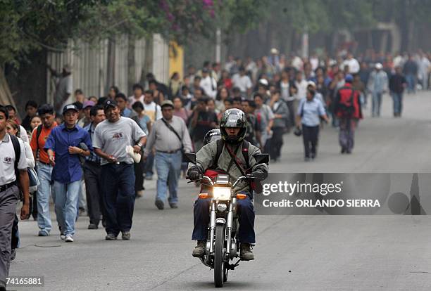 Guatemala City, GUATEMALA: Un motociclista pasa junto a cientos de usuarios del transporte urbano que se dirigen a sus centros de trabajo y de...