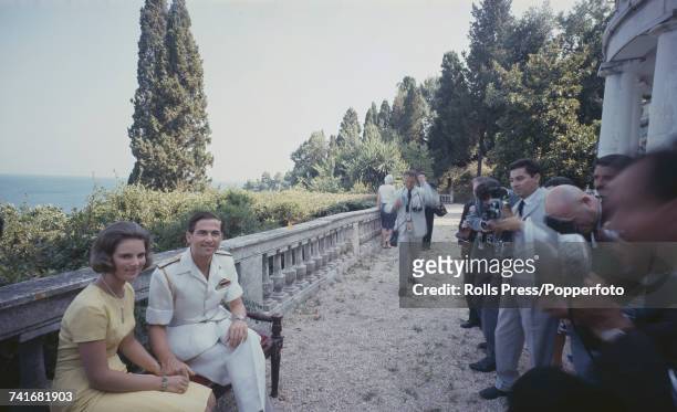 King Constantine II of Greece and his fiancee, Princess Anne-Marie of Denmark pictured together sitting in front of photographers at the Greek royal...