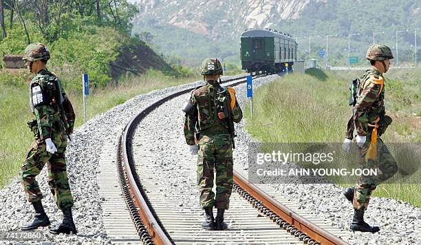 South Korean Army soldiers walk on the rail to close a border gate after a North Korean train, background, crossed the border line to return their...