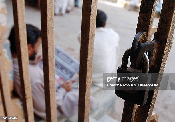 Pakistani men sit outside the locked gate of City court on the lawyers' strike in Karachi, 17 May 2007. Pakistani lawyers countrywide boycotted the...