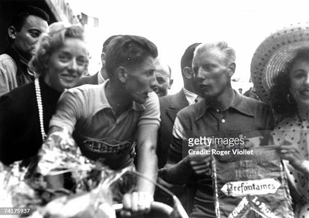 French racing cyclist Jacques Anquetil, winner of the 1957 Tour de France, celebrating his victory with wife Janine, fellow cyclist Andre Darrigade...