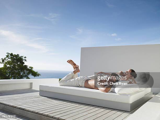 man and woman lying down on bed outdoors with blue sky - romantic young couple sleeping in bed stock pictures, royalty-free photos & images