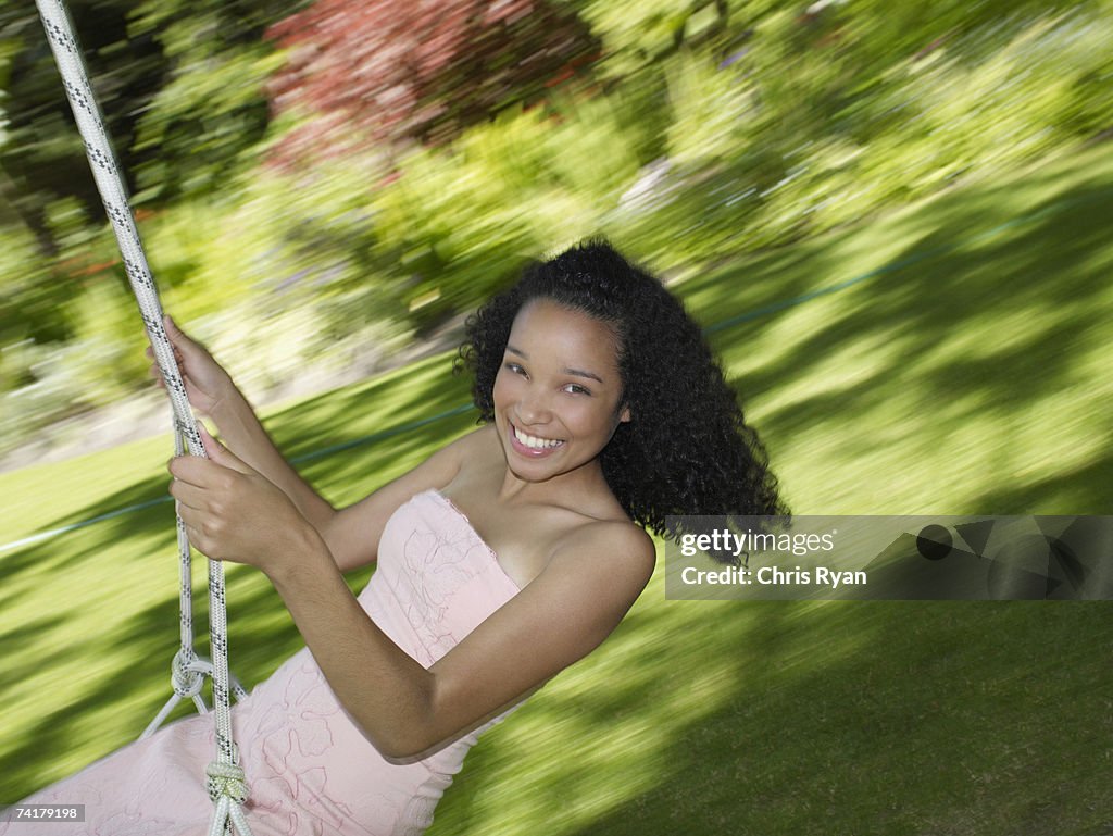 Teenage girl swinging and smiling outdoors with motion blur