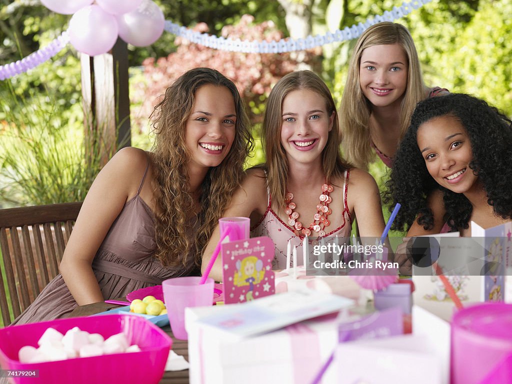 Four teenage girls at birthday party smiling outdoors