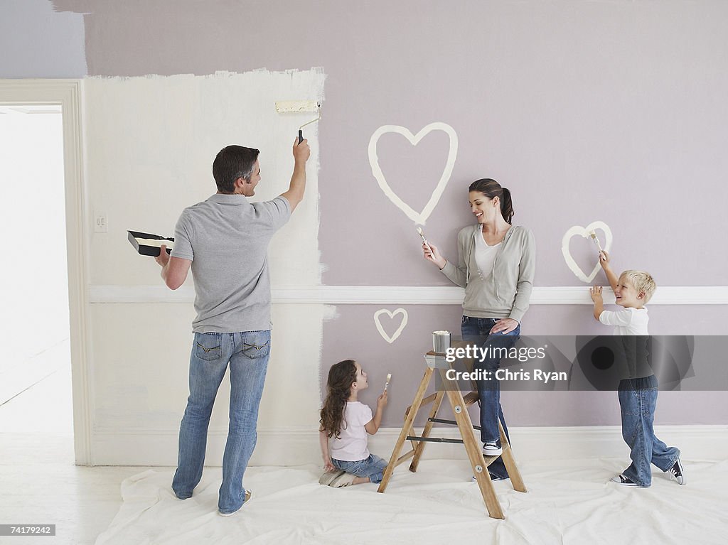Uomo e donna con ragazzo e ragazza dipingere cuori sulla parete