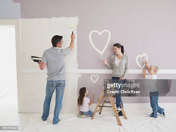 man and woman with boy and girl painting hearts on wall - full body paint stock pictures, royalty-free photos & images