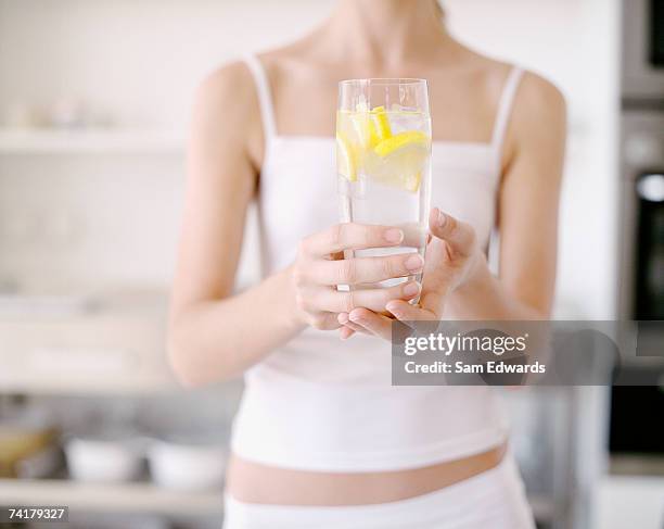 woman holding glass of water with lemon - lemon stock pictures, royalty-free photos & images