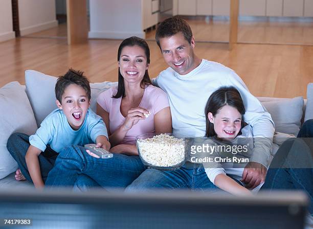 hombre y mujer con niño y niña mirando televisión y comiendo p - familia viendo tv fotografías e imágenes de stock