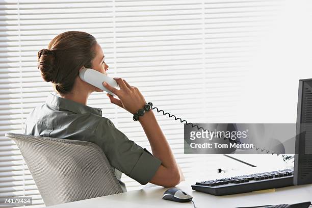 rear view of businesswoman sitting at desk talking on telephone - telefonlur bildbanksfoton och bilder
