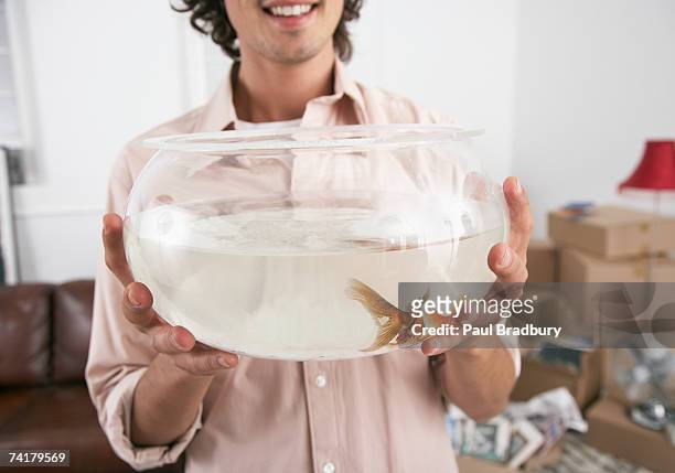 mann hält goldfisch bowl lächeln - fish bowl stock-fotos und bilder
