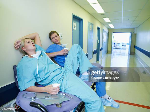 woman and man in scrubs relaxing in hospital - nursing assistant stock pictures, royalty-free photos & images