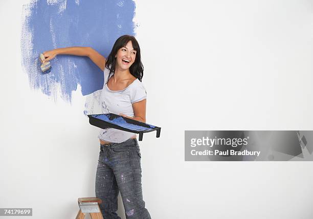 mujer pinta y riendo - pared casa fotografías e imágenes de stock