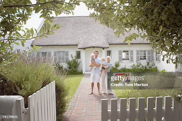 homem e mulher segurando bebês na frente de casa, com - sold single word - fotografias e filmes do acervo