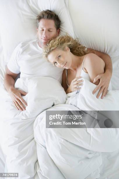 man and woman snuggling in bed asleep - couple cuddling in bed stock pictures, royalty-free photos & images