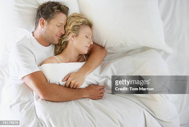 man and woman snuggling in bed asleep - couples in bed stock pictures, royalty-free photos & images