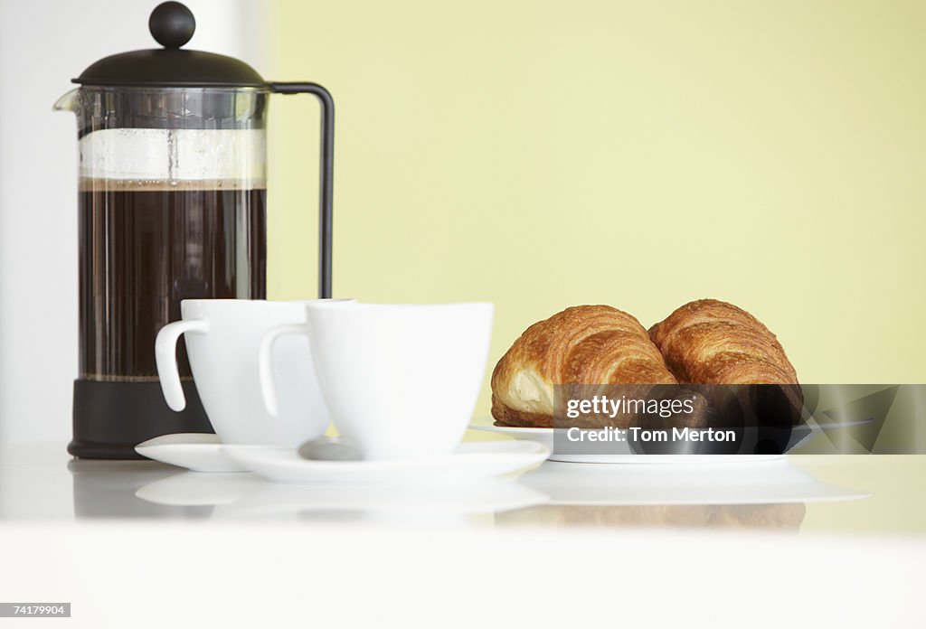 Carafe avec des tasses à café et des croissants