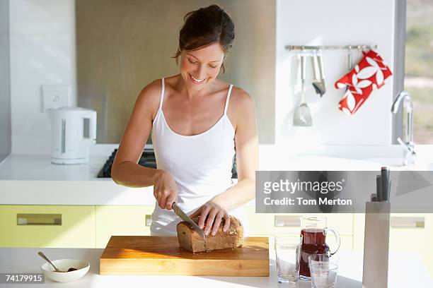 woman in kitchen slicing bread - woman bread stock pictures, royalty-free photos & images