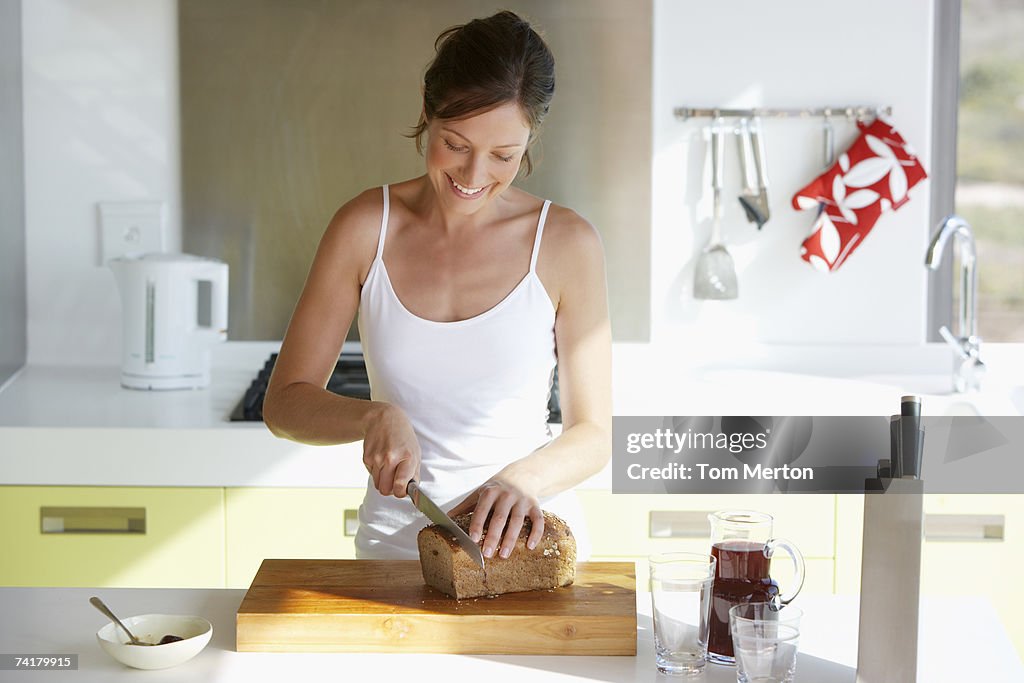 Woman in kitchen slicing bread
