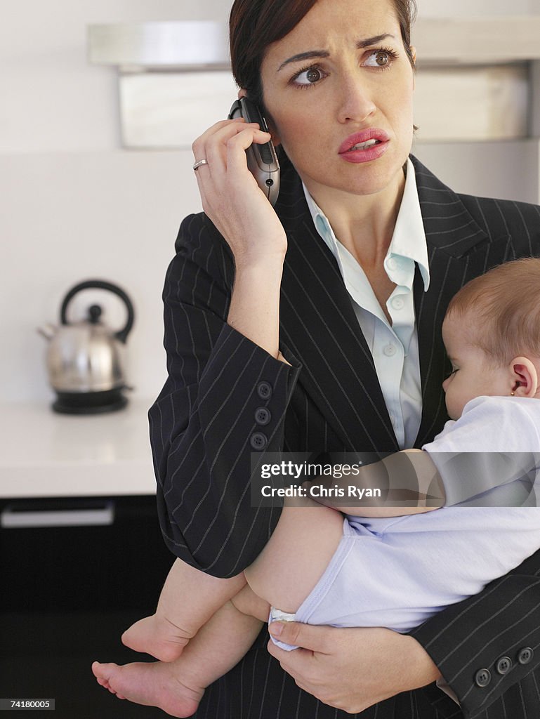 Empresária falando no telefone, segurando o bebê dormindo