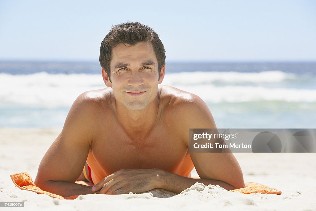 Man lying down on beach towel in sand