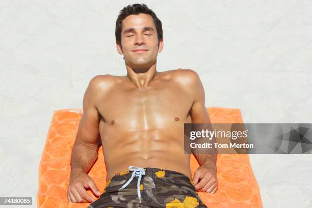 man lying down on beach towel in sand - sunbathing stock pictures, royalty-free photos & images
