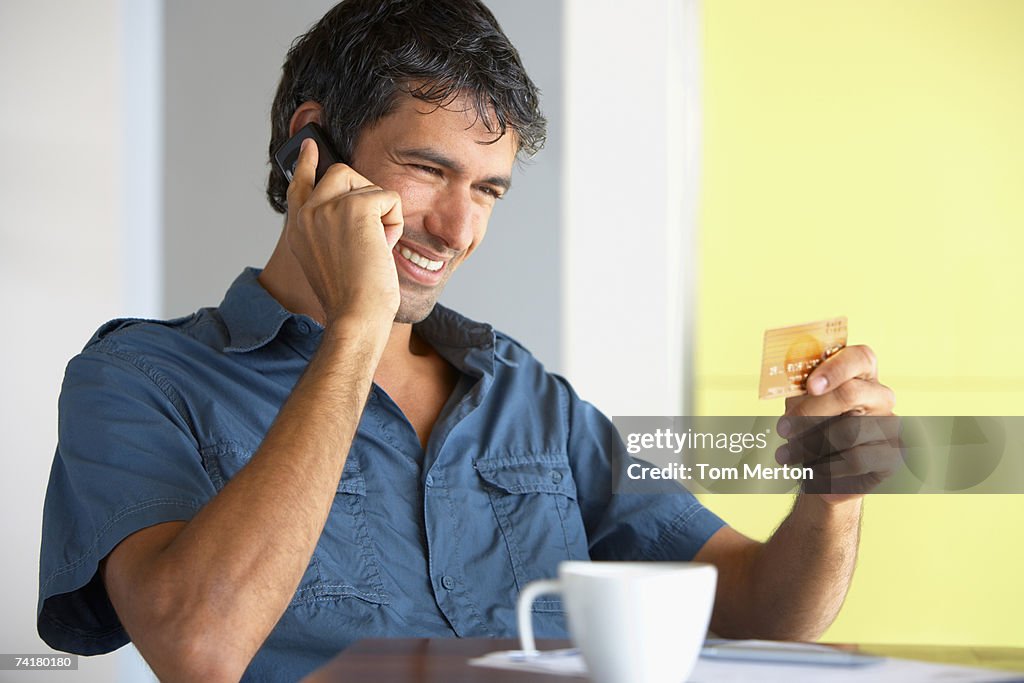 Man on cell phone with credit card and coffee cup