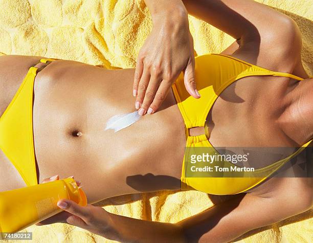 donna in costume da bagno applicare crema solare o sun block - crema solare foto e immagini stock