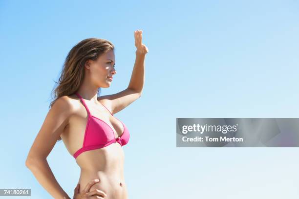 woman in bikini waist up blocking sun with hand - blocking sun stock pictures, royalty-free photos & images