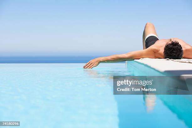 man on infinity pool deck in swimsuit - man pool stock pictures, royalty-free photos & images