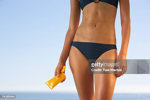 midsection of woman in bikini with sun block - swimwear 個照片及圖片檔